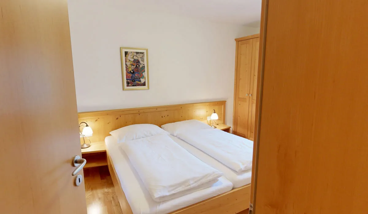 Blick in ein helles Schlafzimmer mit zwei Betten und Holzschränken