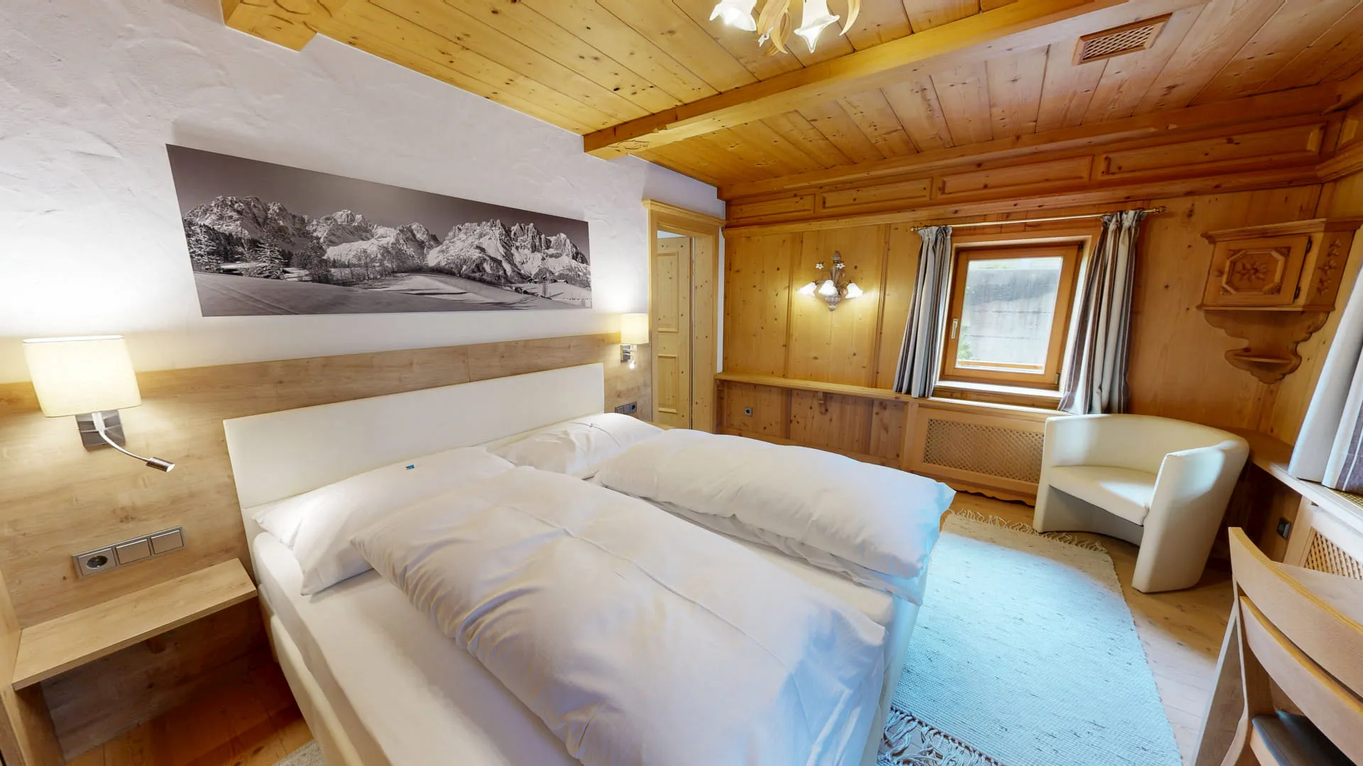 Helles Zimmer mit einem Doppelbett, Holzwänden und Fenster mit Aussicht.